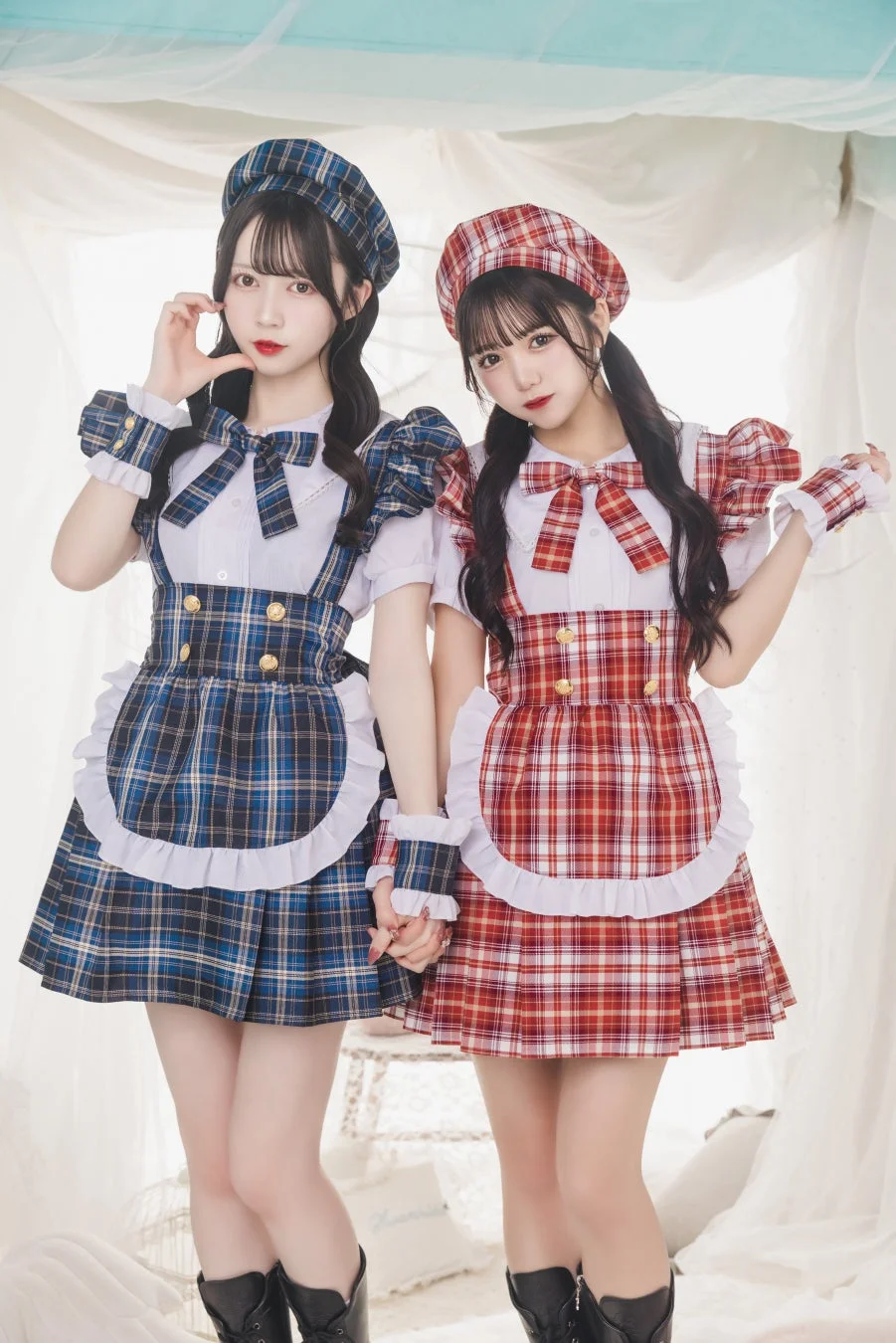 青と赤のチェック柄のメイド服を着た二人の女性が、手をつないでポーズをとっています