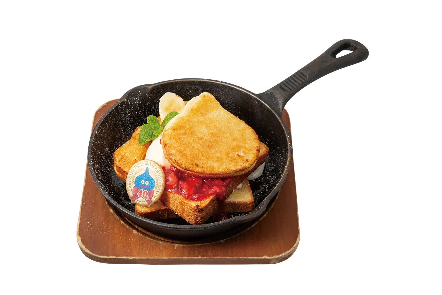 スキレットに盛り付けられた、ドラゴンクエスト40周年記念のスライム型フレンチトーストです。いちごソース、バナナ、ホイップクリームが添えられた、可愛らしいデザートです。