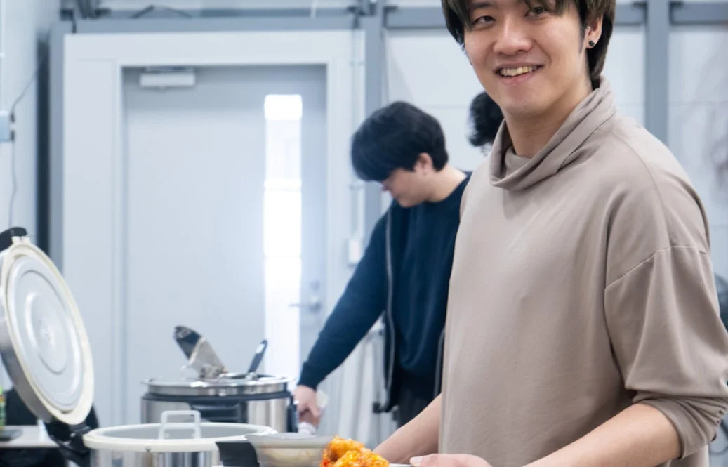 室内で笑顔の男性が料理の皿を持っている様子