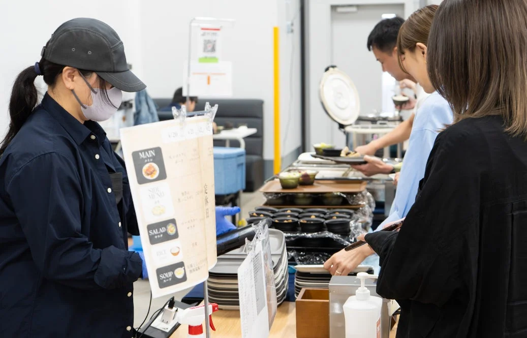 ビュッフェ形式のレストランで、人々が料理を盛り付けている様子