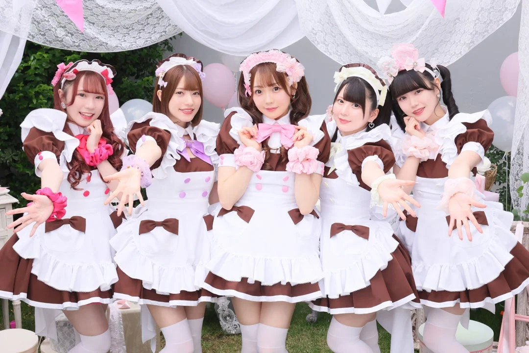 メイド服を着た5人の女性が笑顔でポーズをとる