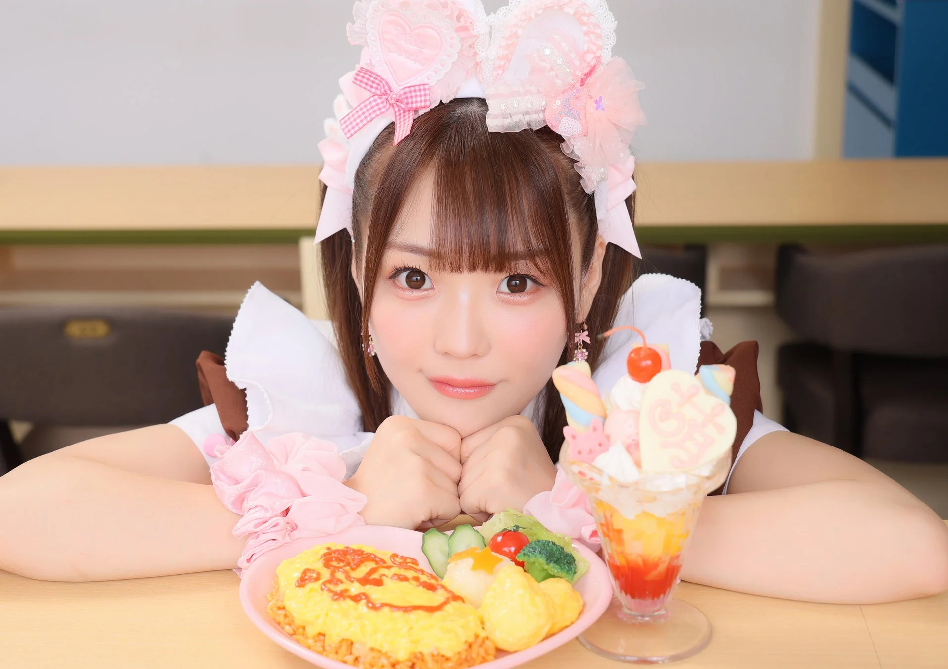 可愛らしいメイドがオムライスとパフェを前に笑顔