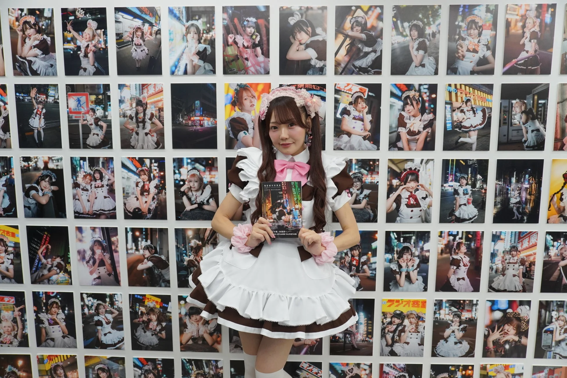 メイド姿の女性が写真展の前に立っています