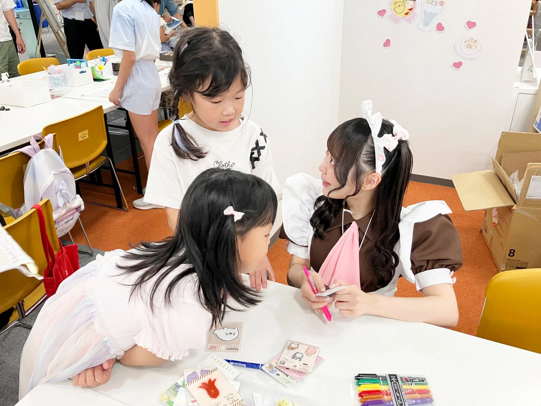 メイドさんが子どもたちにクラフトを教えている様子
