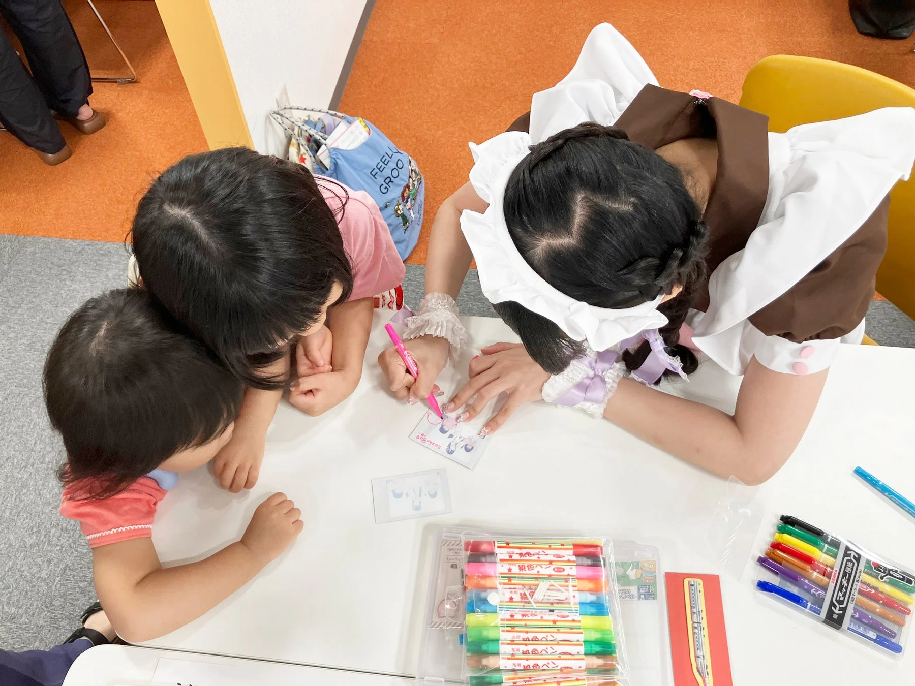 メイドさんと子どもたちが一緒に絵を描いている様子